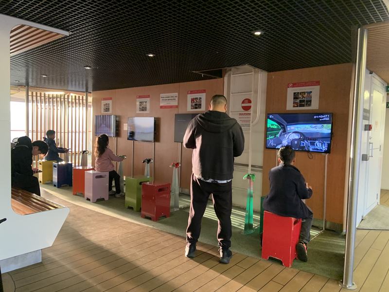 Eleven hours in a chair — A games arcade on board: wall-mounted screens, coloured stools, children and one