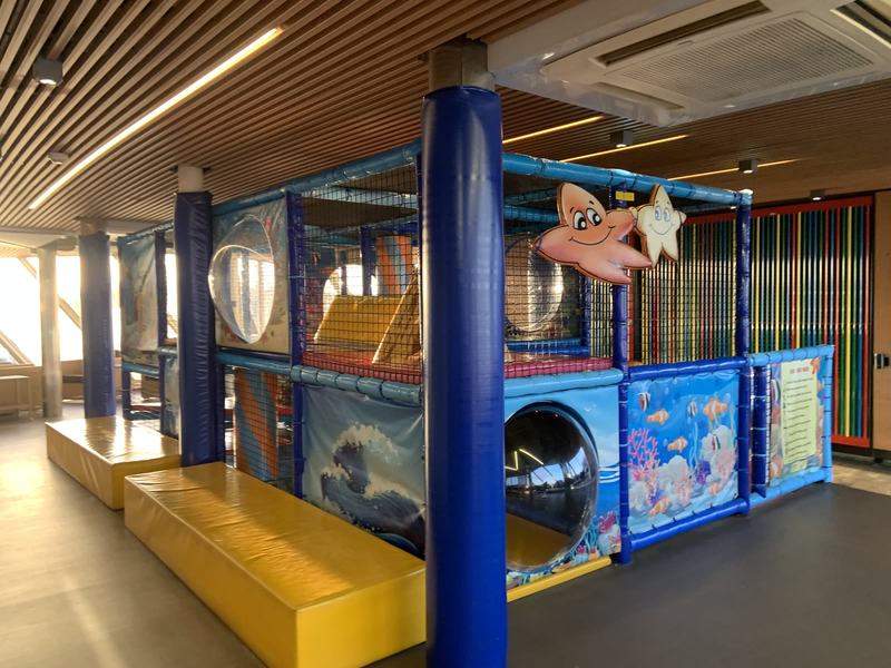 Eleven hours in a chair — The ship's soft-play structure: a netted frame on padded blue posts, yellow padd