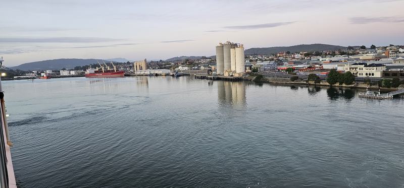Eleven hours in a chair — Devonport from the ship at dawn: the Mersey, a red bulk carrier, cement silos, t
