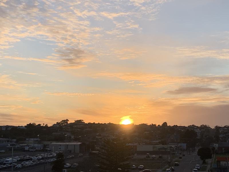 Eleven hours in a chair — The sun breaking over the Devonport rooftops, orange light through thin cloud
