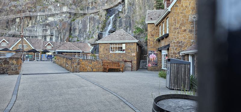 A gorge at the end of the street β The Penny Royal courtyard: stone cottages, a waterfall down the quarry face, rop