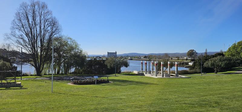 A gorge at the end of the street β A lawn in Royal Park with a row of pale columns banded in red beside a broad str