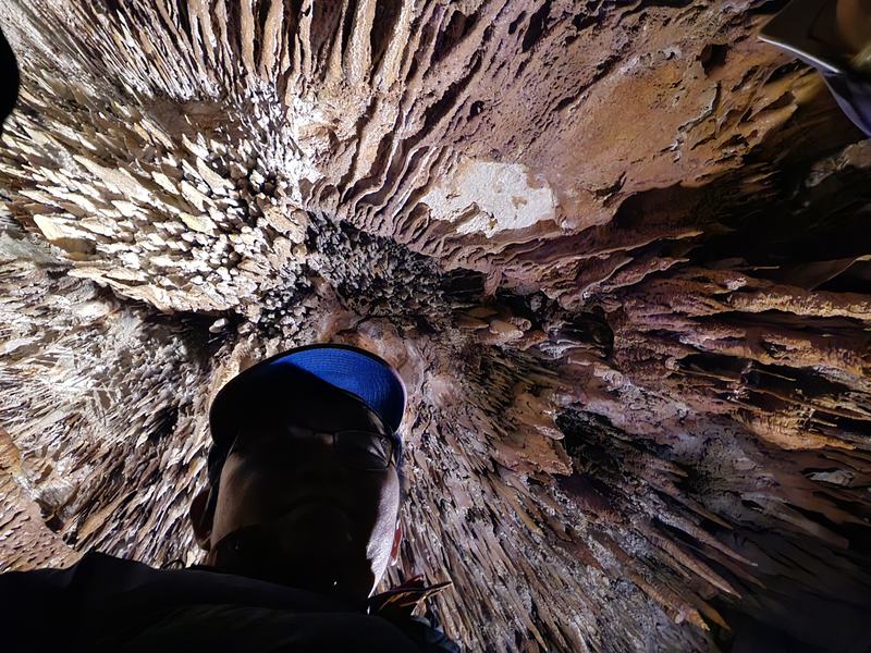 Weindorfer's mountain — Looking straight up at a ceiling bristling with small stalactites, a man in a bl
