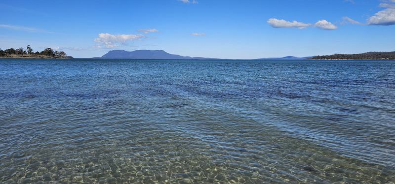 Why it's called Wineglass Bay — Clear shallow water at Raspins Beach, Maria Island's flat-topped mountains acros