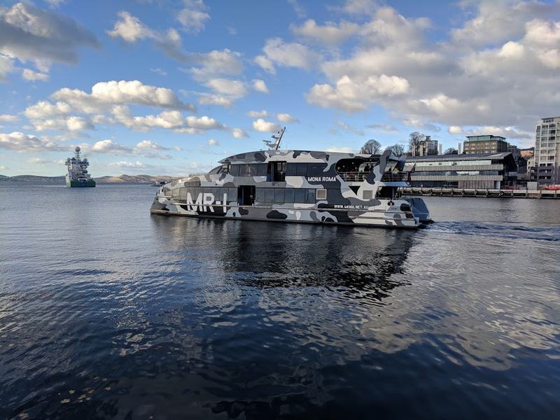 Cut into the cliff β A camouflage-painted MONA catamaran on the Derwent, leaving the Port of Hobart