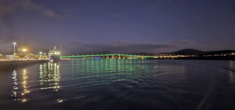 Cut into the cliff β The Tasman Bridge lit green at night across the Derwent, a ship at the wharf on