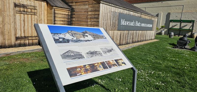 The city that faces south — The Mawson's Huts Replica Museum, with an interpretive sign and a husky-and-sled