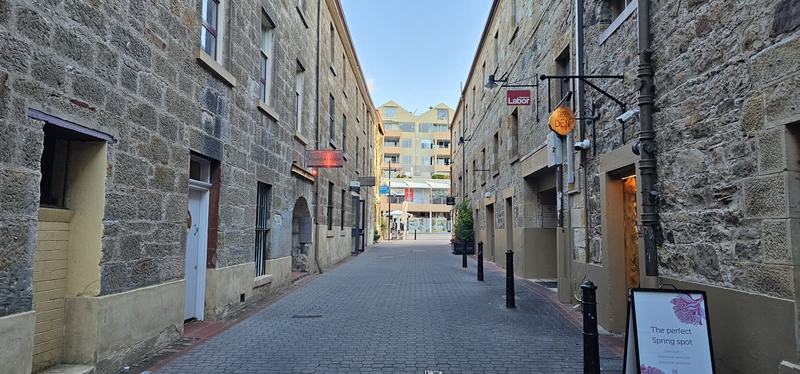 The city that faces south — A laneway between tall sandstone warehouses at Salamanca