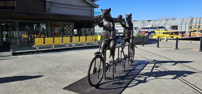 The city that faces south — Two bronze animals on a tandem bicycle by Brooke Street Pier, one holding binocu