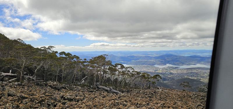 A mountain with four names — A slope of lichen-covered boulders and snow gums, with Hobart and the Derwent fa