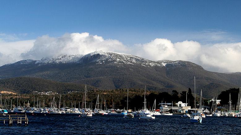 A mountain with four names — kunanyi / Mount Wellington from across the Derwent, snow on the summit, yachts m