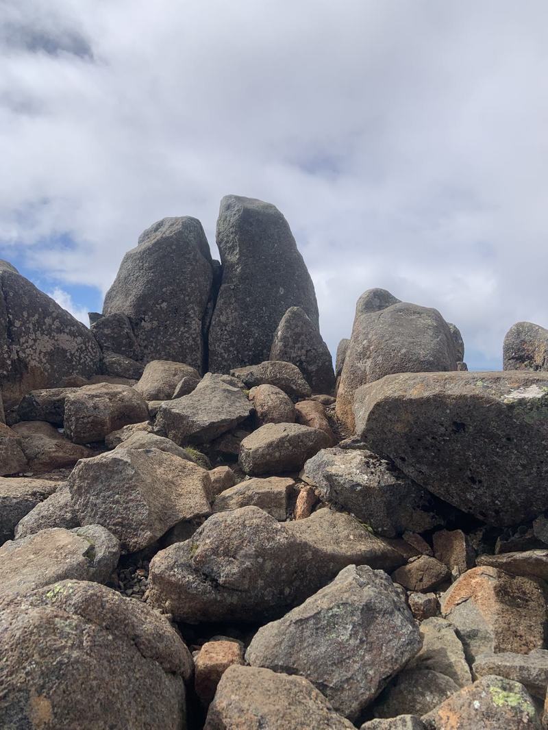 A mountain with four names — Tall weathered dolerite tors stacked above a jumble of boulders, under grey and