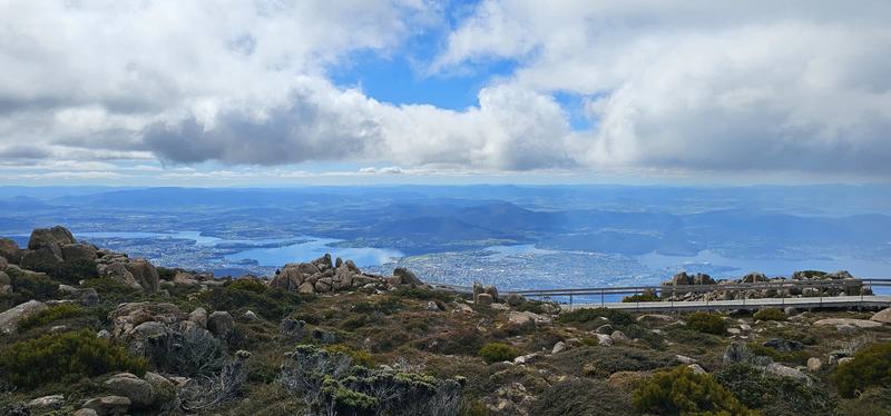 A mountain with four names — The Derwent winding past Hobart's suburbs, seen from the summit rocks under heav