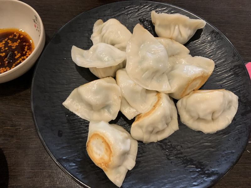 Melbourne anytime — a base, not a checklist — A black plate of dumplings, some pan-fried on one side, with a small dish of chi