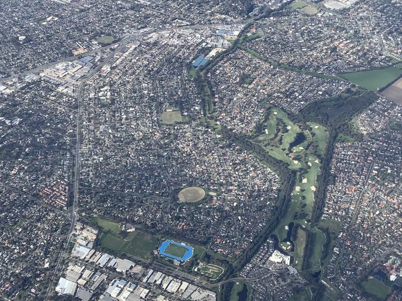 Melbourne anytime — a base, not a checklist — Suburbs of Melbourne from the air, a golf course along a creek, sports ovals and