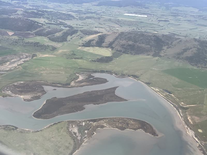 Melbourne anytime — a base, not a checklist — Tidal flats and low islands of saltmarsh in an inlet, with green farmland and dr