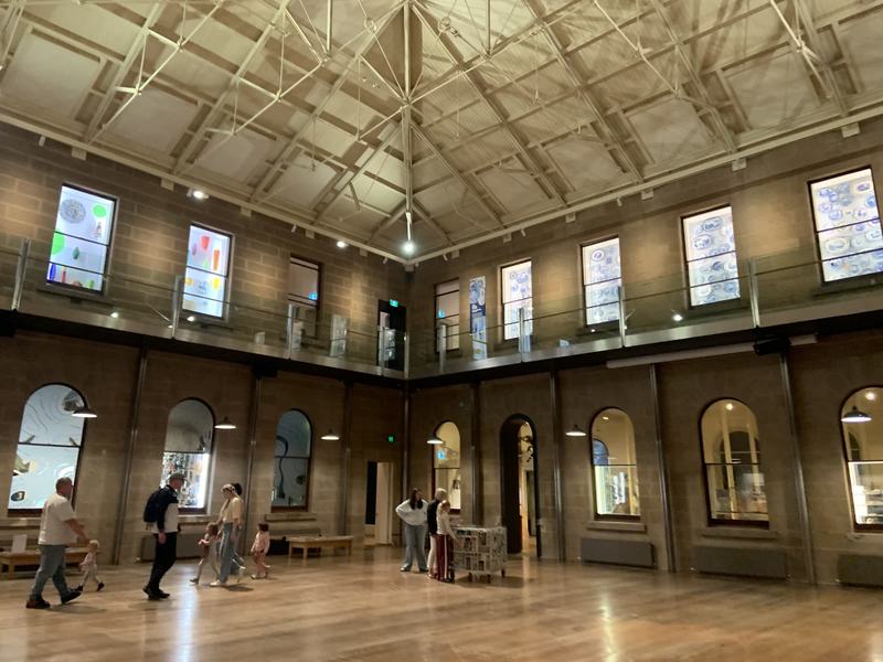 Hobart anytime — a base, not a checklist — A tall stone hall at TMAG with a timber floor, exposed roof trusses, a glazed up