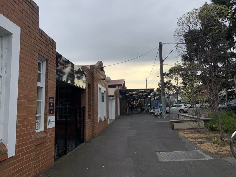 What the gold paid for — A quiet brick street with a low brick building on the left and the market's Food