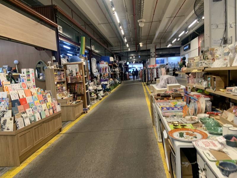 What the gold paid for — A long market aisle with cards and books on the left and colourful plates and ho
