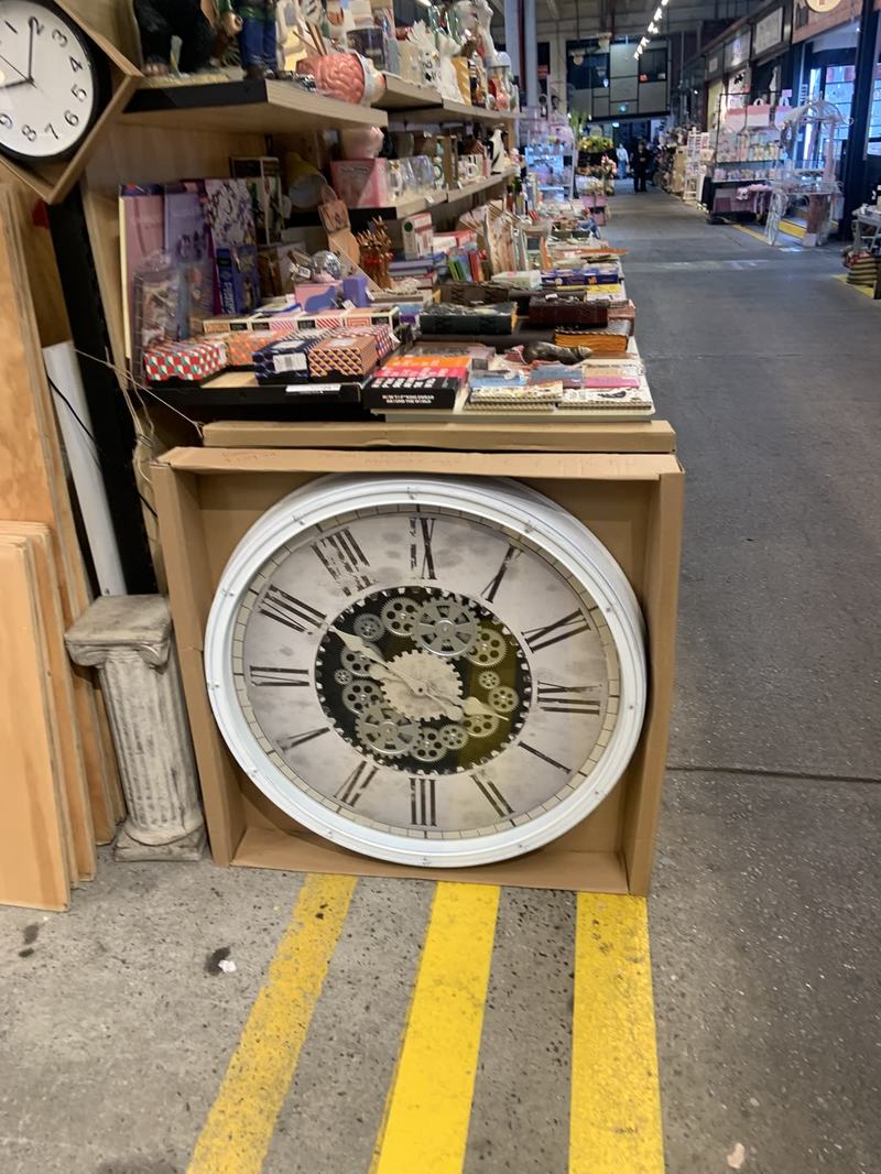 What the gold paid for — A large white wall clock with Roman numerals and visible gears standing in a car
