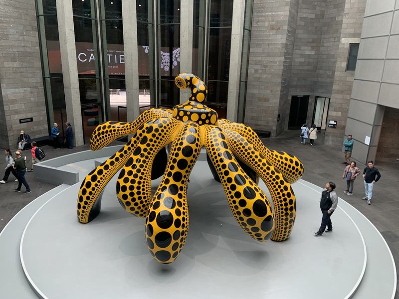 What the gold paid for — Looking down on a large glossy yellow sculpture covered in black dots, standing